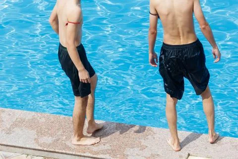 Two men stand at a poolside edge Stock Photos