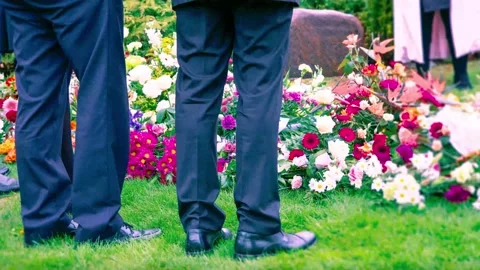 Two men standing in front of funeral flowers on a cemetary Video stock 144221166