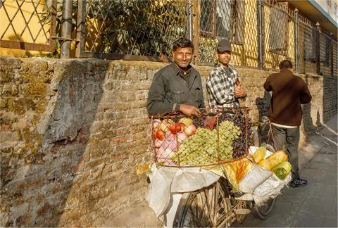 Two men stood by the side of a pathway selling fresh fruit from a bicycle Foto stock