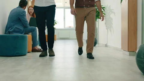 Two men in suits and classic style work shoes are walking down a white office Video stock 166910021