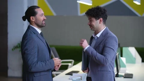 Two men in suits are talking, laughing and smiling in the office Stock Footage 233716935