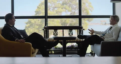 Two men in suits having a business meeting, they sitting near a big window on Stock Footage 146203633