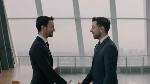 Two men in suits shaking hands and nodding in a happy manner Stock Footage 131033421