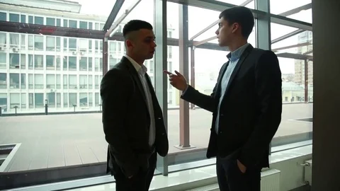 Two men swear on the background of a glass wall. Slow motion. Stock Footage 74304278