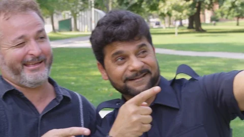 Two men take a selfie together at a park - shot on RED Stock Footage 124717598