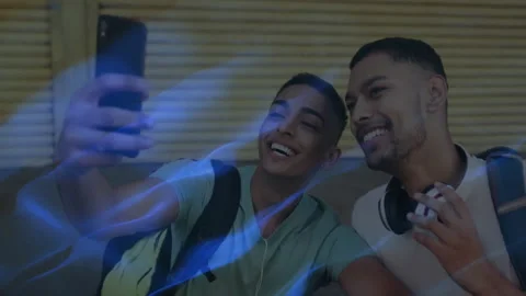 Two men taking selfie with smartphone in street, showing animated blue light Stock Footage 307856958