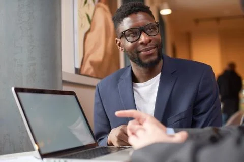 Two men talking to each other while one types on the laptop. Foto stock