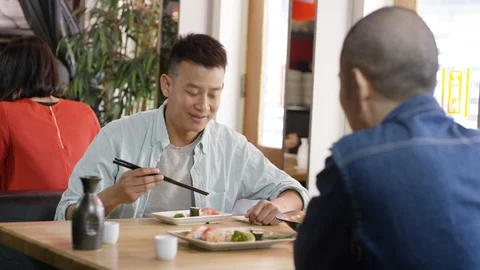 Two men toasting cups while having meal in restaurant Stock Footage 108009330