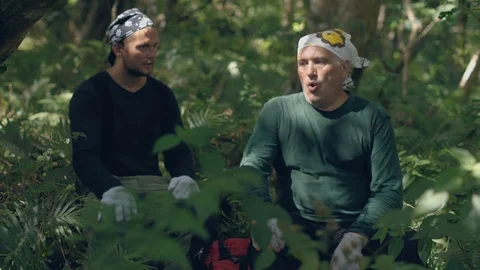 Two men tourists having a rest sitting in forest and talking each other. Stock Footage 116404705