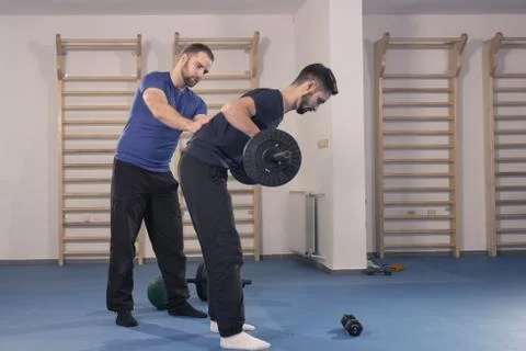 Two men, trainer instructor learning showing educating exercise, weights bar Foto stock
