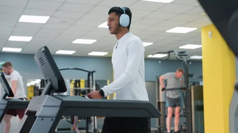 Two men on treadmills and one doing dips in bright modern gym workout scene Video stock 308327771