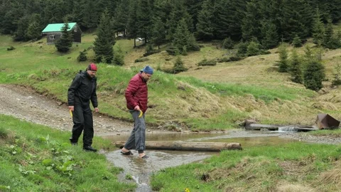 Two Men Trekking Through a Stream Overflowing on a Road in the Ukrainian Ca.. Stock Footage 284932168