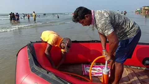 Two men trying to pump air in a inflatable rubber tourist boat. Main source.. Stock Footage 231714184