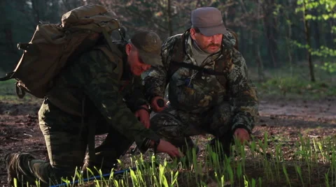 Two men in uniform with backpacks and sticks for walking go along the forest Stock Footage
