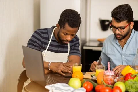 Two men using laptop in kitchen Stock Photos