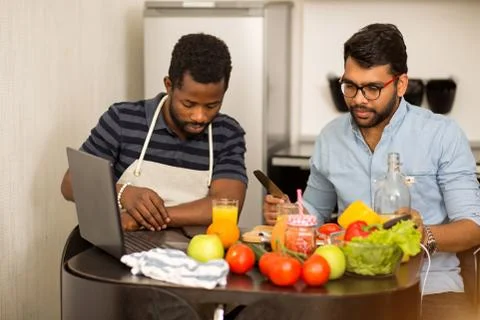 Two men using laptop in kitchen Stock Photos