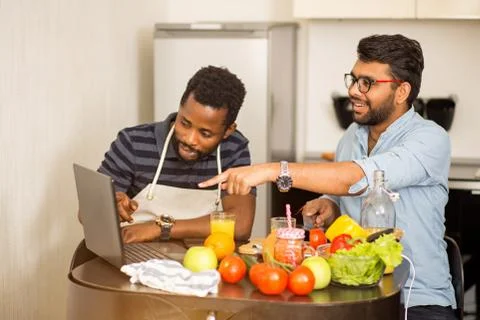Two men using laptop in kitchen Stock Photos