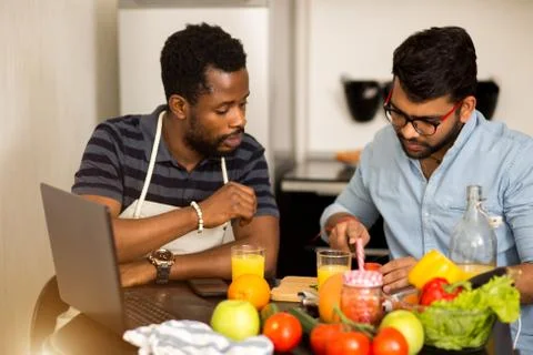 Two men using laptop in kitchen Stock Photos