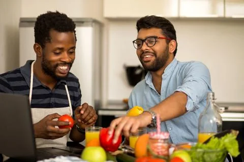 Two men using laptop in kitchen Stock Photos