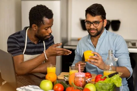 Two men using laptop in kitchen Stock Photos