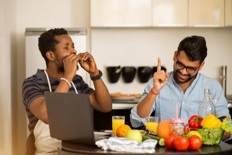 Two men using laptop in kitchen Stock Photos