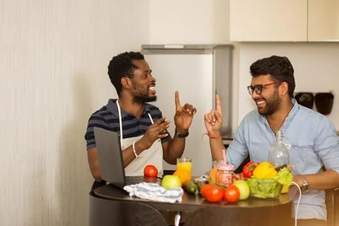 Two men using laptop in kitchen Stock Photos