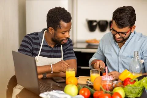 Two men using laptop in kitchen Stock Photos