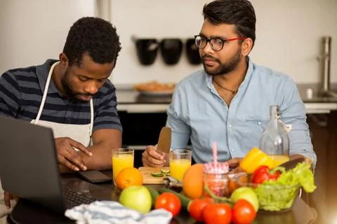 Two men using laptop in kitchen Stock Photos