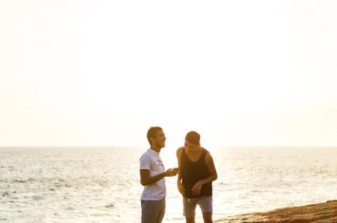 Two men using Smart phones at the edge of the sea, Couple Chatting online Stock Photos