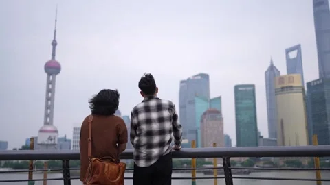 Two men viewing Shanghai skyline from waterfront Stock Footage 346303880