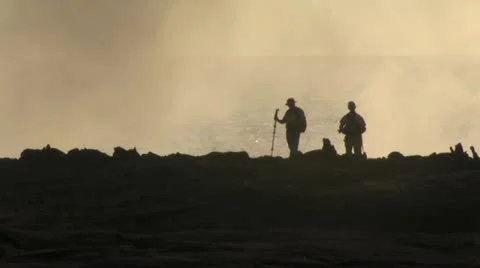 Two Men Walk Across A Volcanic Field With The Ocean In The Background Video stock 19285908