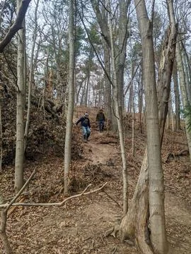 Two men walk down a dirt trail in a forest Stock Photos
