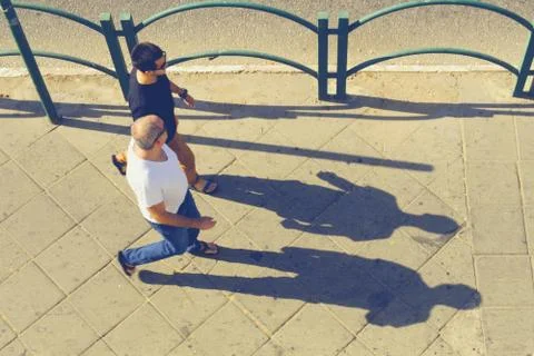 Two men walk down the street and long shadows Stock-Fotos