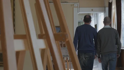 Two men walk through the halls of the art gallery and talk about art Stock Footage 128477136