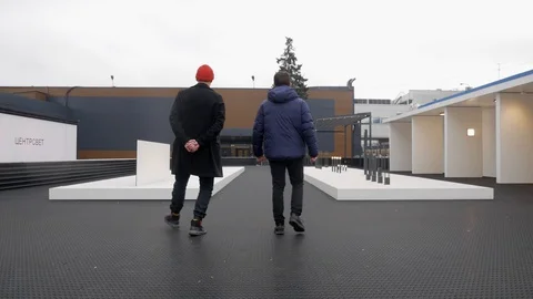 Two men walk through the showroom of light Stock Footage 128104379
