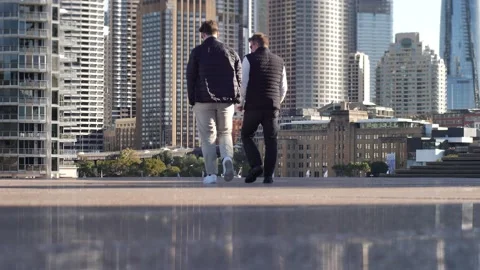 Two men walk towards Circular Quay cityscape in Sydney slow motion 4K Stock Footage 201458408