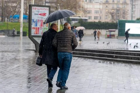 Two men walk under an umbrella on a rainy day in the city. Istanbul Stock Photos