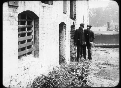 Two men walking around old building in calm village, United Kingdom, 1923 Stock Footage 172219873