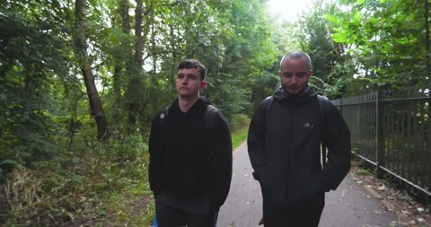 Two men walking on forest path wearing athletic gear, enjoying outdoor exercise Stock Footage 346028420