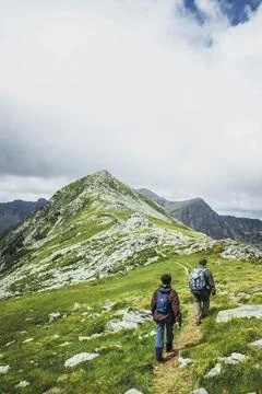 Two Men Walking on a Hill Under White Clouds Stock Photos