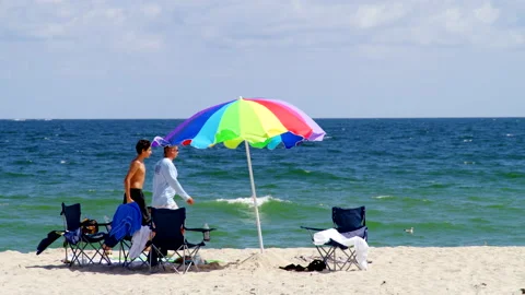 Two men walking on the ocean beach on sunny windy day in Florida Stock Footage 221582560