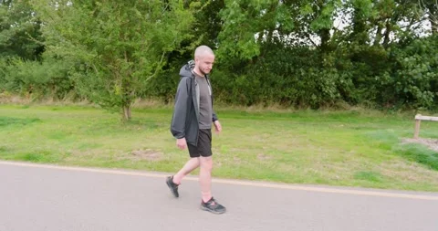Two men walking on park path, enjoying outdoor exercise and conversation trees Stock Footage 345715483
