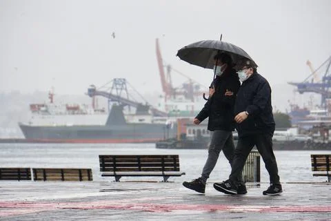 Two men walking under rain with umbrella Stock Photos