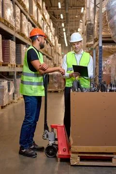 Two men warehouse workers with hand pallet jack lift stand having talk, temwork Fotos Stock