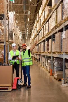 Two men warehouse workers with hand pallet jack lift stand having talk, temwork Fotos Stock