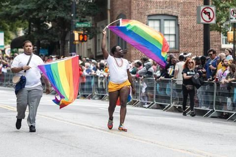 Two men wave pride flags walking in annual Atlanta parade Stock Photos