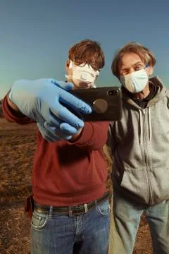 Two men wearing protective face mask on public city location shooting selfie Stock Photos