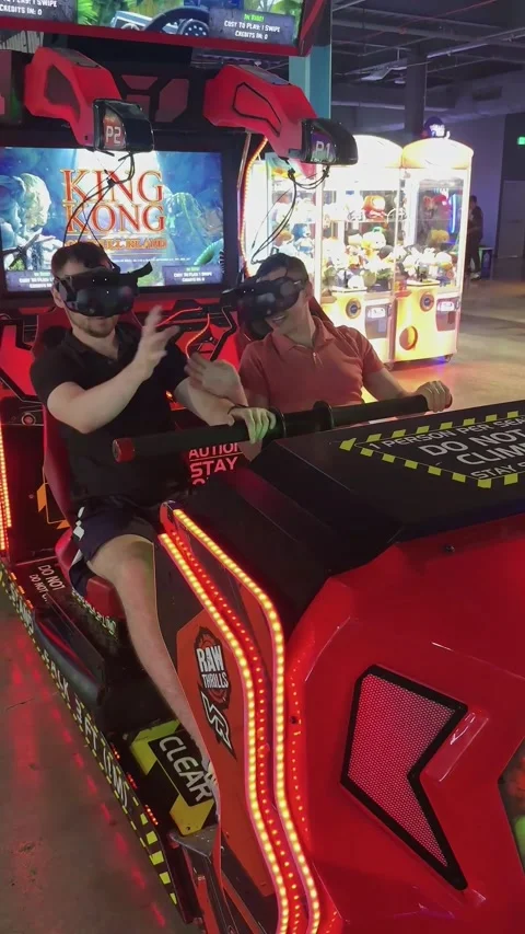 Two men wearing virtual reality headsets and playing VR arcade game Stock Footage 335750725