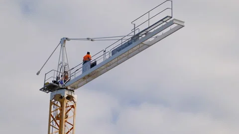 Two men work on dismantling a crane - one passes tool to other. View upwards Stock Footage 196143889