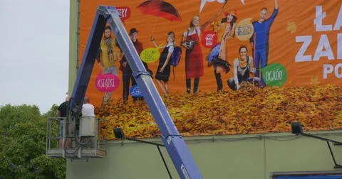 Two Men Workers in Truck Tower Are Installing Orange Advertisement Banner into Stock Footage 54838482